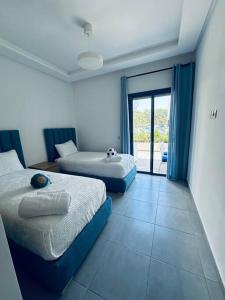 a bedroom with two beds and a door to a patio at Martil Costa-Mar in Martil +42 photos