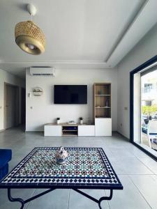 a living room with a table and a tv at Martil Costa-Mar in Martil