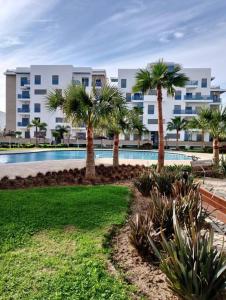 a resort with a swimming pool and palm trees at Martil Costa-Mar in Martil