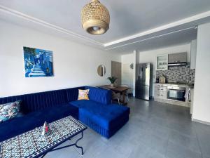 a living room with a blue couch and a kitchen at Martil Costa-Mar in Martil