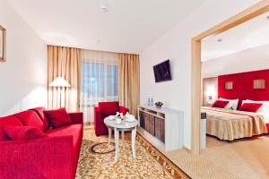 バラシハにあるEast Gate Hotelの赤いソファとベッドが備わるホテルルームです。