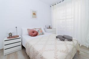 a white bedroom with a white bed and a window at Harmonia in Punta Prima +19 photos