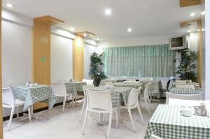 ein Restaurant mit weißen Tischen und Stühlen und einem Fernseher in der Unterkunft Jupiter Suites in Manila