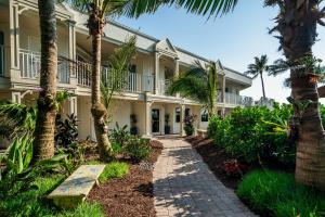 a large building with palm trees and a walkway at Vanderbilt Beach Resort in Naples