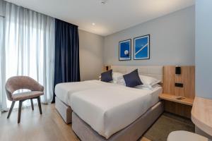 a hotel room with a large bed and a chair at Hotel A'mare in Zadar