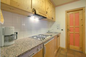 a kitchen with wooden cabinets and a counter top at Ciasa La Ro in San Cassiano