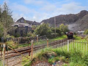 a train traveling down the tracks in front of a house at Nyth Yr Eryr in Blaenau-Ffestiniog +13 photos