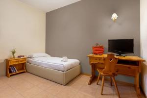 una camera da letto con un letto e una scrivania con una televisione di Agritur Eden Marone a Riva del Garda