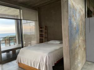 ein Schlafzimmer mit einem Bett und einem großen Fenster in der Unterkunft Loft Horizonte Arte 2 in Puerto Escondido