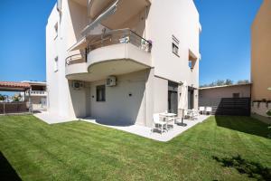 Kalopsia Luxury Apartment Near Chania في مدينة خانيا: مبنى أبيض كبير مع ساحة عشب