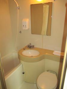 a bathroom with a sink and a toilet and a mirror at HOTEL LiVEMAX Mihara Ekimae in Mihara