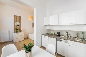 a kitchen with white cabinets and a white table and chairs at Ruhige und stilvolle Wohnung am Clara-Zetkin-Park in Leipzig