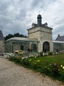 a building with a greenhouse and flowers in the yard at Château de la Thibaudière - Chambre des oiseaux in Allonnes