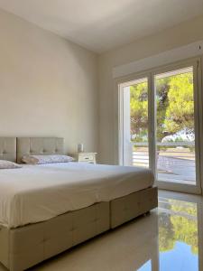 a bedroom with a large bed and a large window at Casa del Parco - Salento Homes in Melendugno +5 photos