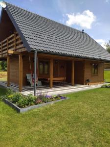 a log cabin with a porch and flowers in front of it at Dom letniskowy Krzyś in Przejma Wielka