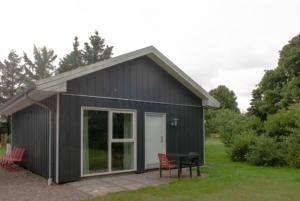a black shed with a table and chairs in a yard at Greenstudio in Tjæreborg