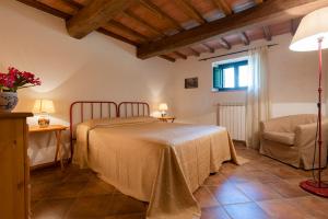 a bedroom with a bed and a chair at Fattoria Javello - Agriturismo La Casaccia in Montemurlo