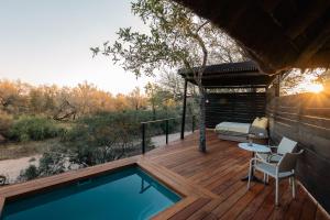 a deck with a pool and a bed and a table at Thornybush Simbambili Lodge in Sabi Sand Game Reserve
