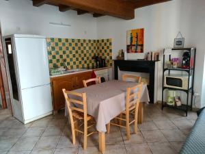 a kitchen with a table with chairs and a refrigerator at OLMETA DI TUDA - T3 in Olmeta-di-Tuda