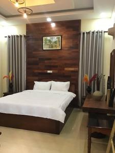 een slaapkamer met een groot bed met een houten wand bij Liza Boutique in Phumĭ Ta Phŭl