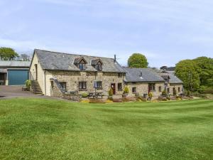 a large stone house with a large yard at Smiddy Cottage, Historic Village Hub with Spacious Lounge, High Ceilings, and Wood Stove in Dulverton