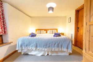 a bedroom with a large bed with blue sheets at Smiddy Cottage, Historic Village Hub with Spacious Lounge, High Ceilings, and Wood Stove in Dulverton
