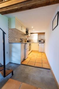 a kitchen with white appliances and a wooden ceiling at Smiddy Cottage, Historic Village Hub with Spacious Lounge, High Ceilings, and Wood Stove in Dulverton