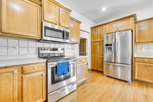 a kitchen with wooden cabinets and stainless steel appliances at Pet-Friendly Johnston Getaway with Deck and Yard! in Johnston