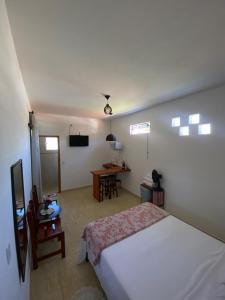 ein Schlafzimmer mit einem Bett und einem Schreibtisch mit einem Fernseher in der Unterkunft Hospedaria Porto de Paz 2 in Cunha