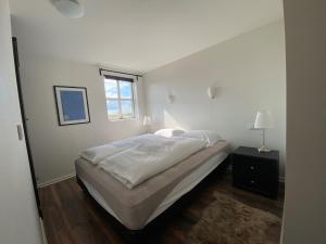 a white bedroom with a bed and a window at Myrarkot Country Home in Selfoss