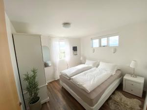 a white bedroom with a bed and a mirror at Myrarkot Country Home in Selfoss
