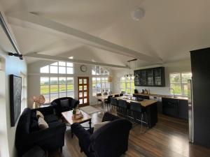 a living room with black furniture and a kitchen at Myrarkot Country Home in Selfoss