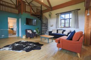 a living room with a red chair and a blue couch at Kiri - Charming Cottage Perfect for Large Groups & Family in Dulverton