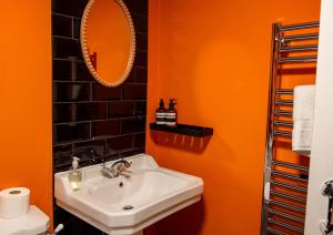 an orange bathroom with a sink and a mirror at Kiri - Charming Cottage Perfect for Large Groups & Family in Dulverton +24 photos