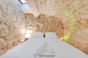 Un dormitorio con una cama en una pared de piedra. en Charming flat with Jacuzzi heart of Paris GetHosted, en París 5 fotos más