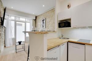 Una cocina con gabinetes blancos y encimera. en Charming flat with Jacuzzi heart of Paris GetHosted, en París