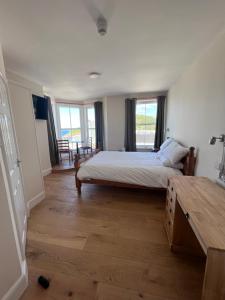 a bedroom with a bed and a table and windows at The Harbour Lights in Ilfracombe