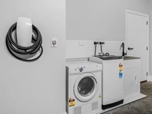 a washer and dryer in a white laundry room at Central Studio in new townhouse in Beechworth