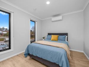 un dormitorio con una cama y una ventana en Brand new 3 bed townhouse walk to town, en Beechworth