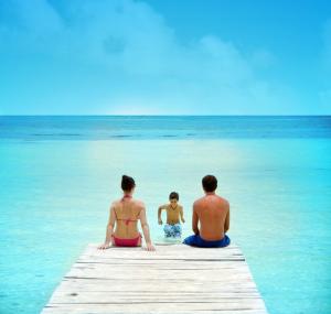 a group of three people sitting on a dock in the ocean at Oasis Palm - All Inclusive in Cancún