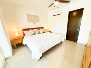 a bedroom with a bed with white sheets and pillows at Spacious Apartment with Terrace, Pool and Beach Access in Puerto Aventuras