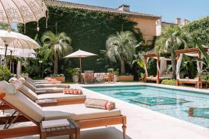 a pool with chaise lounges and umbrellas at Airelles Pan Dei Palais in Saint-Tropez