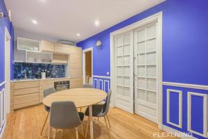 une salle à manger avec des murs bleus et une table et des chaises dans l'établissement Flexliving - room - Neuilly-sur-Seine, à Neuilly-sur-Seine