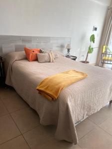 Una cama grande con almohadas naranjas encima. en Loft D-Oro, en Comodoro Rivadavia