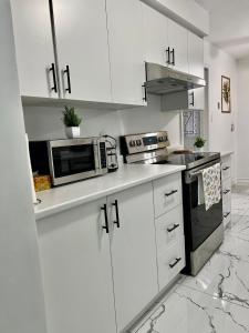 a white kitchen with white cabinets and a microwave at K9 Room Near Airport in Mississauga