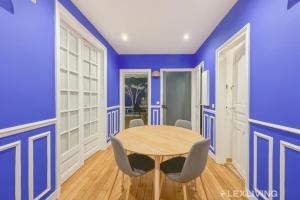 une salle à manger avec des murs bleus et une table et des chaises dans l'établissement Flexliving - room - Neuilly-sur-Seine, à Neuilly-sur-Seine
