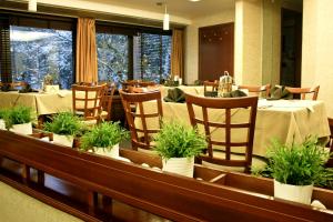 a restaurant with tables and chairs with potted plants at Edi Hotel in Sofia