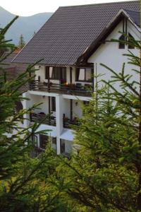 a white building with a black roof and some trees at Cetina in Ranca