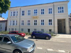 two cars parked in a parking lot in front of a building at Apartament MINI MAX in Kielce