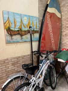 a bike parked next to a surfboard on a wall at Casa espaçosa 6 min da praia in Bertioga